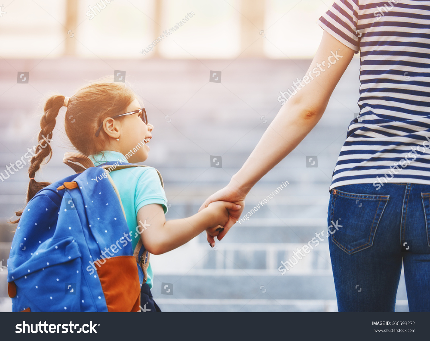stock-photo-parent-and-pupil-of-primary-school-go-hand-in-hand-woman-and-girl-with-backpack-behind-the-back-666593272